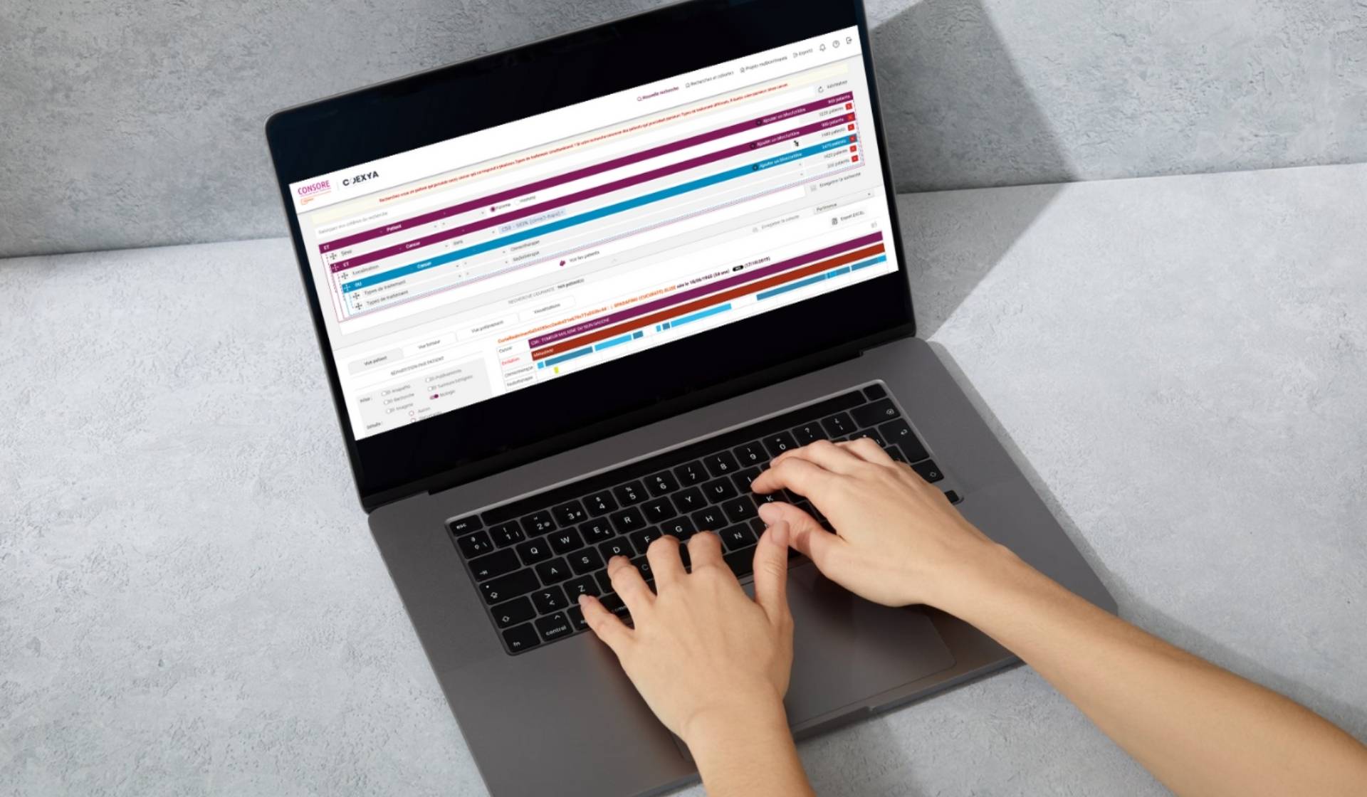 Mains tapant sur un ordinateur portable affichant l’interface de ConSoRe, un outil de data mining pour la recherche en cancérologie.